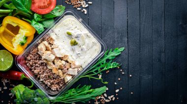 Buğday eti ve taze sebze ile. Sağlıklı bir diyet yemek. Öğle Yemeği boks. Siyah ahşap arka plan üzerinde. Üstten Görünüm. Metin için boş alan.