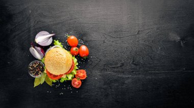 Peynir, et, domates ve soğan ve otlar ile hamburger. Ahşap arka plan üzerinde. Üstten Görünüm. Boş alan.
