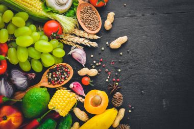 Çiğ sebze, meyve ve baharat bir siyah ahşap yüzey üzerinde büyük bir seçim. Metniniz için boş alan. Üstten Görünüm.