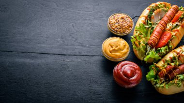 Sosis ızgara sosis, hardal ve ketçap, soğan ve Yeşiller ahşap arka plan üzerinde. Üstten Görünüm. Boş alan.