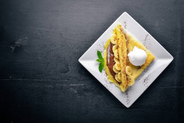 Çikolata ve muz krep. Tatlı. Ahşap bir arka plan üzerinde. Üstten Görünüm. Metniniz için boş alan.