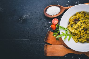 Ispanak, zeytin ve parmesan peyniri ile mantarlı makarna. İtalyan yemeği. Bir siyah ahşap yüzeye. Metniniz için boş alan. Üstten Görünüm.