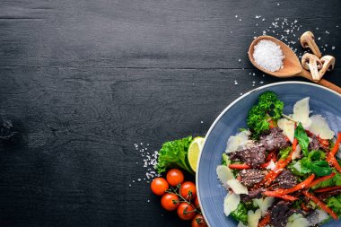 Dana eti ve taze sebze salatası. Ahşap bir arka plan üzerinde. Üstten Görünüm. Metniniz için boş alan.