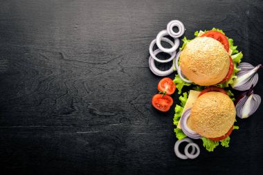 Peynir, et, domates ve soğan ve otlar ile hamburger. Ahşap arka plan üzerinde. Üstten Görünüm. Boş alan.