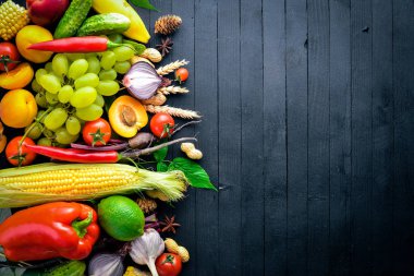 Çiğ sebze ve meyveler siyah ahşap bir masa üzerinde geniş yelpazesi. Metniniz için boş alan. Üstten Görünüm.