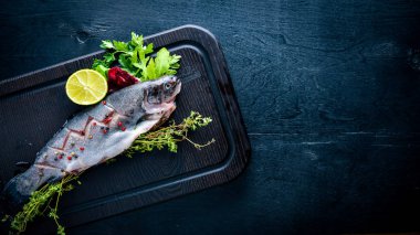 Balık alabalık aromatik otlar ve baharatlar ile. Ahşap arka plan üzerinde.