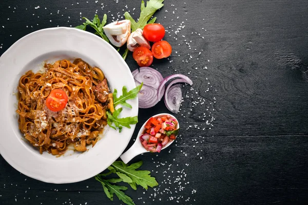 Pasta dengan tomat ceri, zaitun, dan jamur dengan keju parmesan. Makanan Italia. Pada permukaan kayu hitam. Ruang kosong untuk SMSmu. Tampilan atas . — Stok Foto