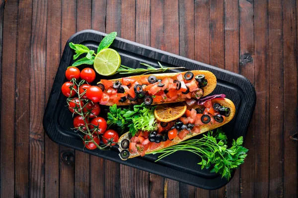 Bruschetta domates, zeytin, otlar ve parmesan peyniri ekmeğin. Soğuk aperatifler. İtalyan mutfağı. Ahşap arka plan üzerinde.