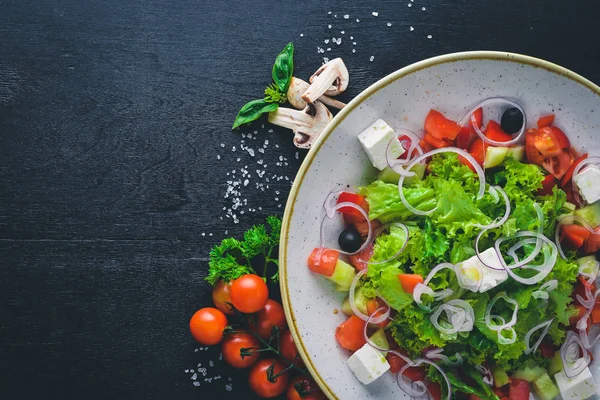 Greek salad of fresh vegetables and cheese. On a wooden background. Top view. Free space for your text. — Stock Photo, Image