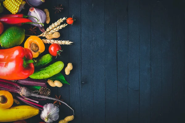 Çiğ sebze ve meyveler siyah ahşap bir masa üzerinde geniş yelpazesi. Metniniz için boş alan. Üstten Görünüm.