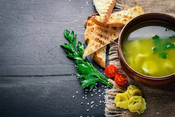 Suyu mantı ve otlar. İtalyan mutfağı. Ahşap bir arka plan üzerinde. Üstten Görünüm. Metniniz için boş alan.