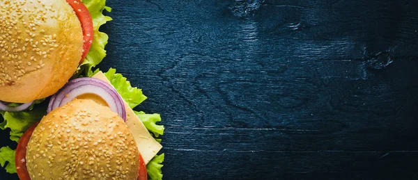 Hambúrguer com queijo, carne, tomate e cebola e ervas. Sobre fundo de madeira. Vista superior. Espaço livre . — Fotografia de Stock