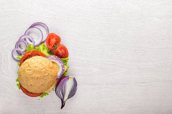 Peynir, et, domates ve soğan ve otlar ile hamburger. Ahşap arka plan üzerinde. Üstten Görünüm. Boş alan.