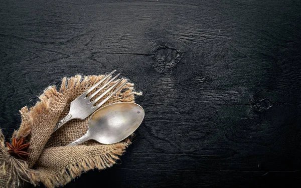 Cutlery, spoon and fork in old fabric on Wooden background. Top view. Free space. — Stock Photo, Image