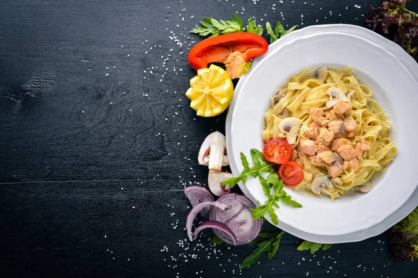 Pastırma, domates, zeytin ve parmesan peyniri ile mantarlı makarna. İtalyan yemeği. Bir siyah ahşap yüzeye. Metniniz için boş alan. Üstten Görünüm.