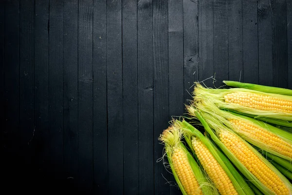 Maïs. Rauwe groenten op een zwarte houten achtergrond. Bovenaanzicht. Vrije ruimte voor uw tekst. — Stockfoto
