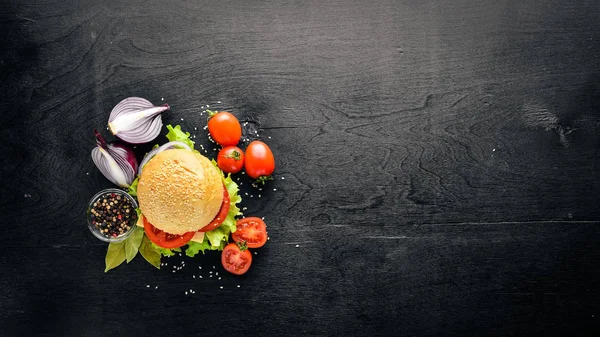 Peynir, et, domates ve soğan ve otlar ile hamburger. Ahşap arka plan üzerinde. Üstten Görünüm. Boş alan.