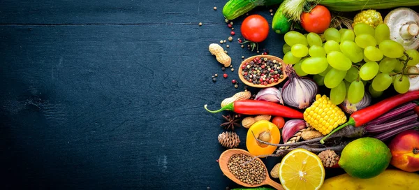 Çiğ sebze, meyve ve baharat bir siyah ahşap yüzey üzerinde büyük bir seçim. Metniniz için boş alan. Üstten Görünüm.