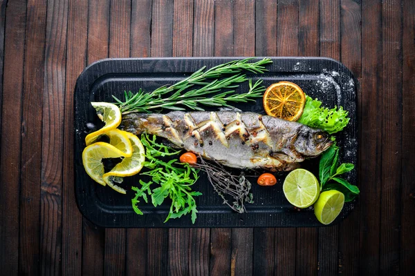 Alabalık balık pişmiş aromatik otlar ve baharatlar ile. Ahşap arka plan üzerinde.