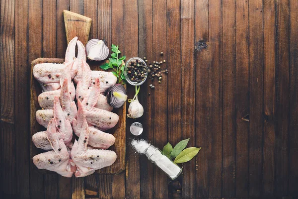 Baharat ile çiğ tavuk kanatları. Ahşap yüzeyde. Üstten Görünüm.