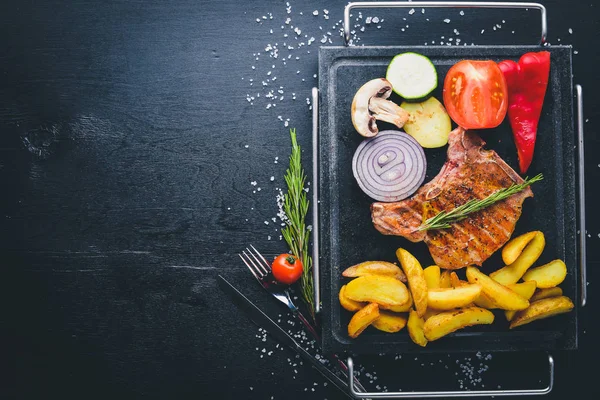 Biftek, patates ve taze sebze. Ahşap bir arka plan üzerinde. Üstten Görünüm. Metniniz için boş alan.