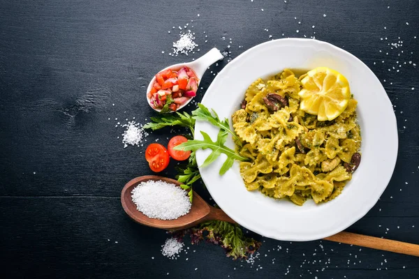 Ispanak, zeytin ve parmesan peyniri ile mantarlı makarna. İtalyan yemeği. Bir siyah ahşap yüzeye. Metniniz için boş alan. Üstten Görünüm.