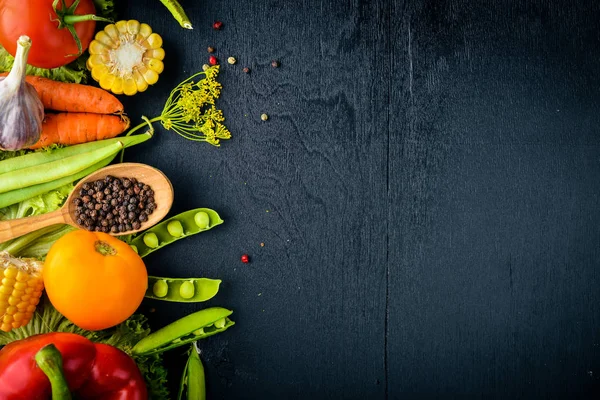 Büyük bir seçim çiğ taze sebze ve baharat. Siyah ahşap arka plan üzerinde. Üstten Görünüm. Metniniz için boş alan.