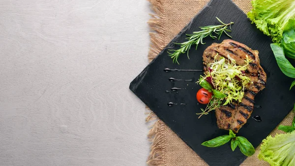 Dana biftek ızgarada pişirilir. Ahşap bir arka plan üzerinde. En iyi bir daha gözden geçirme. Boş alan.