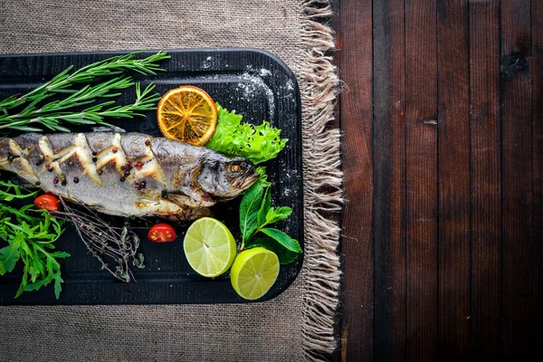 Alabalık balık pişmiş aromatik otlar ve baharatlar ile. Ahşap arka plan üzerinde.