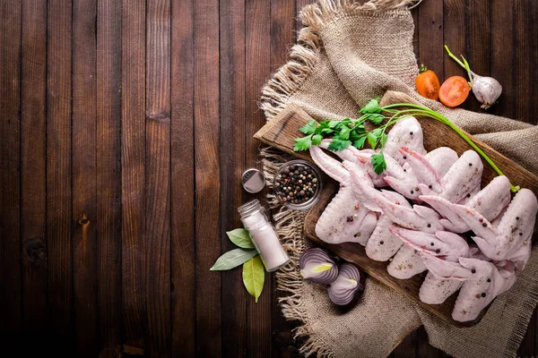 Baharat ile çiğ tavuk kanatları. Ahşap yüzeyde. Üstten Görünüm.