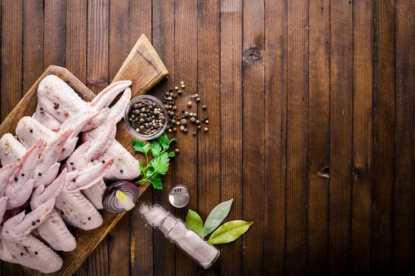 Baharat ile çiğ tavuk kanatları. Ahşap yüzeyde. Üstten Görünüm.