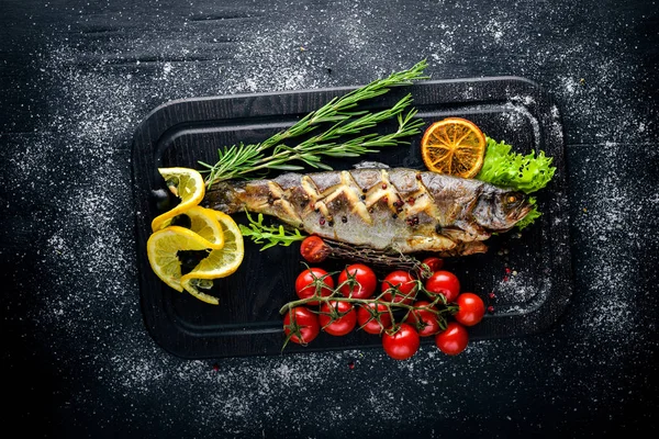 Alabalık balık pişmiş aromatik otlar ve baharatlar ile. Ahşap arka plan üzerinde.