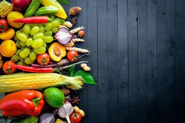Çiğ sebze ve meyveler siyah ahşap bir masa üzerinde geniş yelpazesi. Metniniz için boş alan. Üstten Görünüm.