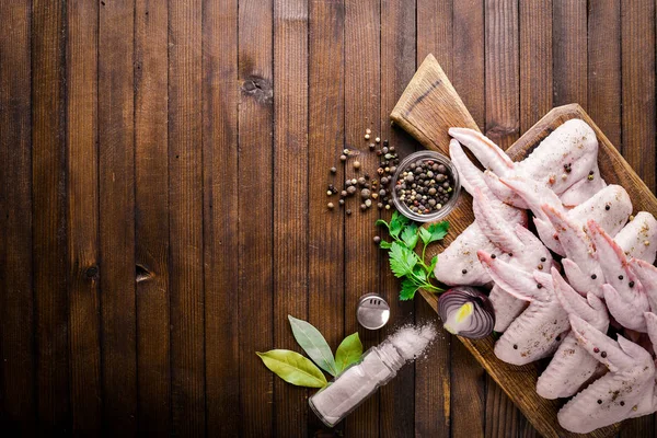 Baharat ile çiğ tavuk kanatları. Ahşap yüzeyde. Üstten Görünüm.