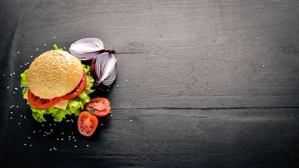 Peynir, et, domates ve soğan ve otlar ile hamburger. Ahşap arka plan üzerinde. Üstten Görünüm. Boş alan.