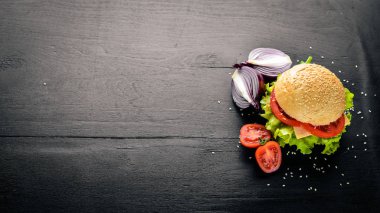 Peynir, et, domates ve soğan ve otlar ile hamburger. Ahşap arka plan üzerinde. Üstten Görünüm. Boş alan.