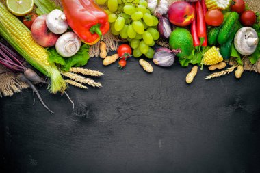 Çiğ sebze ve meyveler siyah ahşap bir masa üzerinde geniş yelpazesi. Metniniz için boş alan. Üstten Görünüm.