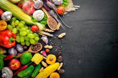Çiğ sebze, meyve ve baharat bir siyah ahşap yüzey üzerinde büyük bir seçim. Metniniz için boş alan. Üstten Görünüm.