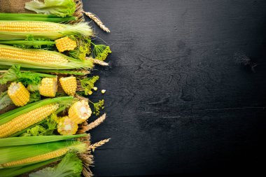 Mısır. Çiğ sebze siyah bir ahşap zemin üzerine. Üstten Görünüm. Metniniz için boş alan.