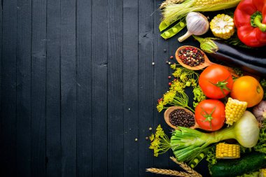 Büyük bir seçim çiğ taze sebze ve baharat. Siyah ahşap arka plan üzerinde. Üstten Görünüm. Metniniz için boş alan.