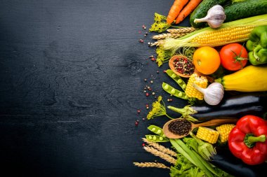 Büyük bir seçim çiğ taze sebze ve baharat. Siyah ahşap arka plan üzerinde. Üstten Görünüm. Metniniz için boş alan.