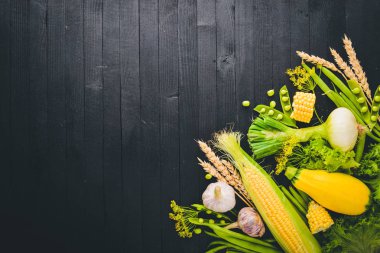 Çok çeşitli ham taze sebze. Mısır, kabak, marul, yeşillik. Siyah ahşap arka plan üzerinde. Üstten Görünüm. Metniniz için boş alan.