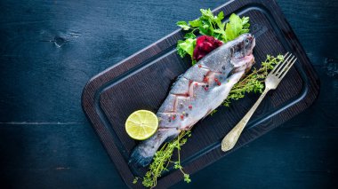 Balık alabalık aromatik otlar ve baharatlar ile. Ahşap arka plan üzerinde.