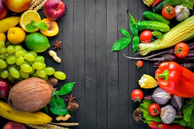 Çiğ sebze ve meyveler siyah ahşap bir masa üzerinde geniş yelpazesi. Metniniz için boş alan. Üstten Görünüm.