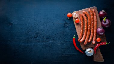 Taze sebze ile bir tavada ızgara sosis. Siyah yüzeyi ahşap. Üstten Görünüm.