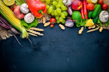 Çiğ sebze ve meyveler siyah ahşap bir masa üzerinde geniş yelpazesi. Metniniz için boş alan. Üstten Görünüm.