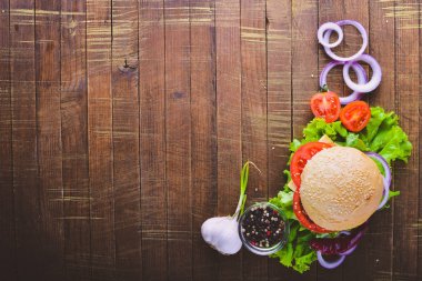 Peynir, et, domates ve soğan ve otlar ile hamburger. Ahşap arka plan üzerinde. Üstten Görünüm. Boş alan.