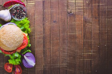 Peynir, et, domates ve soğan ve otlar ile hamburger. Ahşap arka plan üzerinde. Üstten Görünüm. Boş alan.