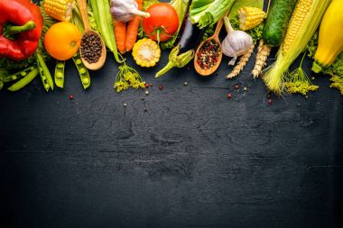 Büyük bir seçim çiğ taze sebze ve baharat. Siyah ahşap arka plan üzerinde. Üstten Görünüm. Metniniz için boş alan.