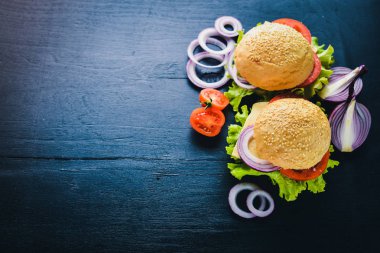 Peynir, et, domates ve soğan ve otlar ile hamburger. Ahşap arka plan üzerinde. Üstten Görünüm. Boş alan.